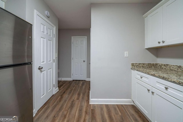 kitchen featuring white cabinetry, dark hardwood / wood-style floors, stainless steel fridge, and light stone counters