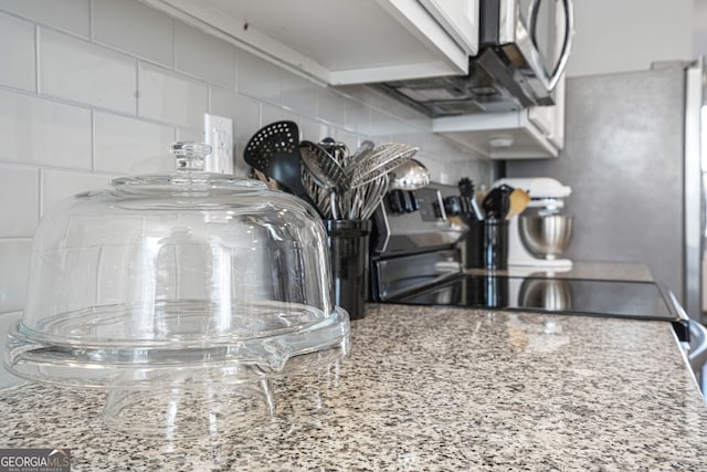 details featuring tasteful backsplash, range with electric cooktop, and light stone counters