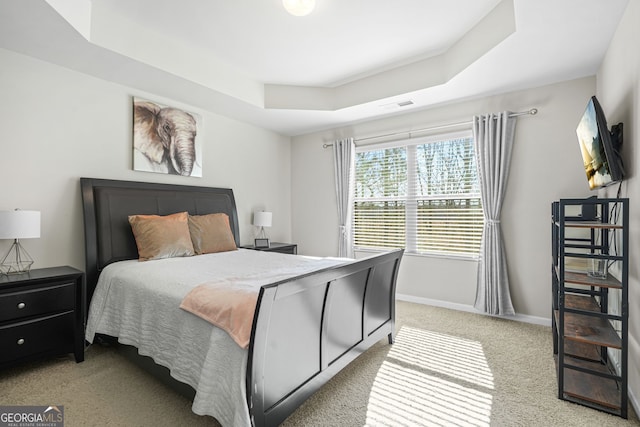 bedroom with a raised ceiling and light carpet