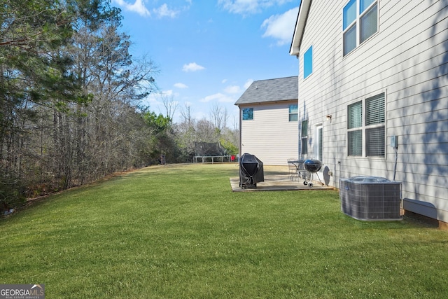 view of yard featuring a trampoline, central AC, and a patio area