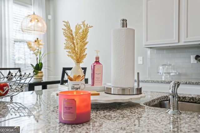 interior space featuring light stone countertops, hanging light fixtures, decorative backsplash, and white cabinets