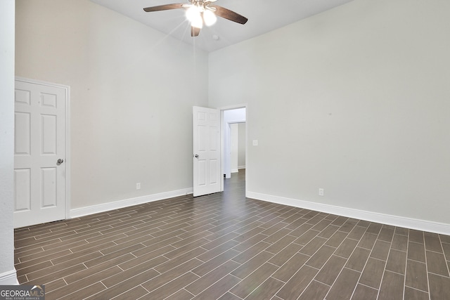 spare room featuring a towering ceiling, dark wood-type flooring, and ceiling fan