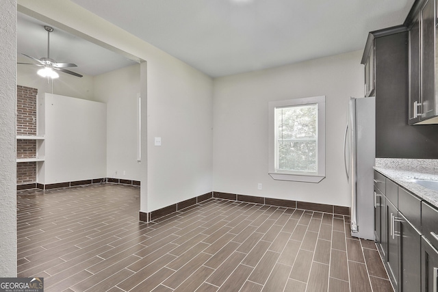 kitchen with stainless steel fridge, light stone countertops, and ceiling fan