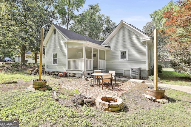 rear view of property with a porch, a patio, and a fire pit