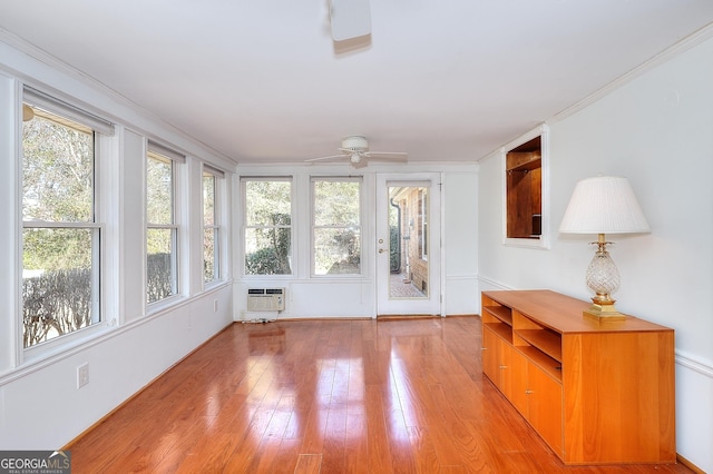 unfurnished sunroom with ceiling fan, a wall unit AC, and a wealth of natural light