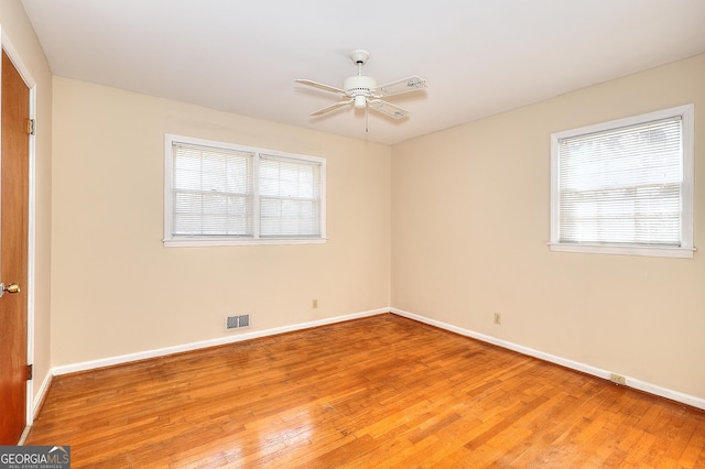 unfurnished room featuring hardwood / wood-style flooring, a wealth of natural light, and ceiling fan