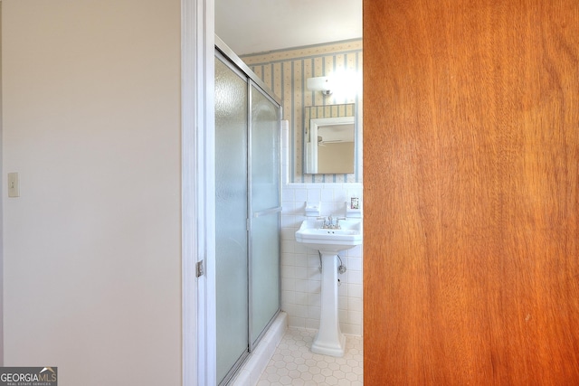 bathroom with tile patterned flooring, a shower with door, and tile walls