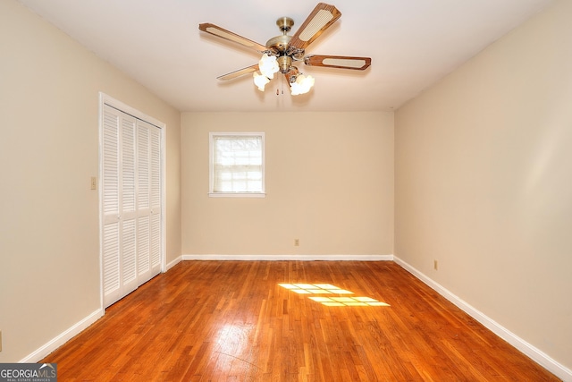 unfurnished bedroom with hardwood / wood-style floors, ceiling fan, and a closet