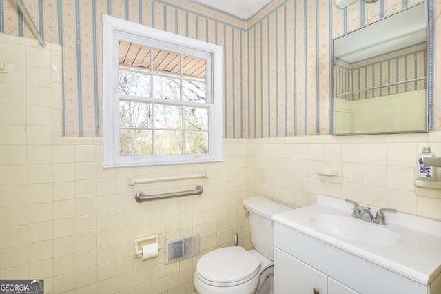 bathroom featuring vanity, tile walls, and toilet