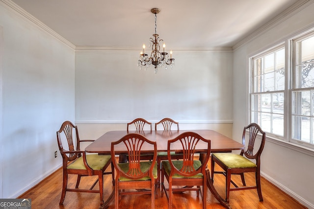 dining room featuring wood-type flooring, ornamental molding, and a notable chandelier