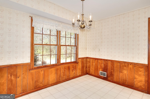 unfurnished room with a chandelier and wood walls