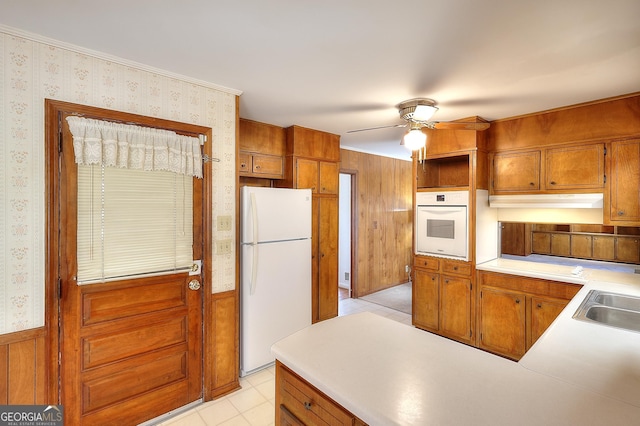 kitchen featuring sink, white appliances, light tile patterned floors, kitchen peninsula, and ceiling fan