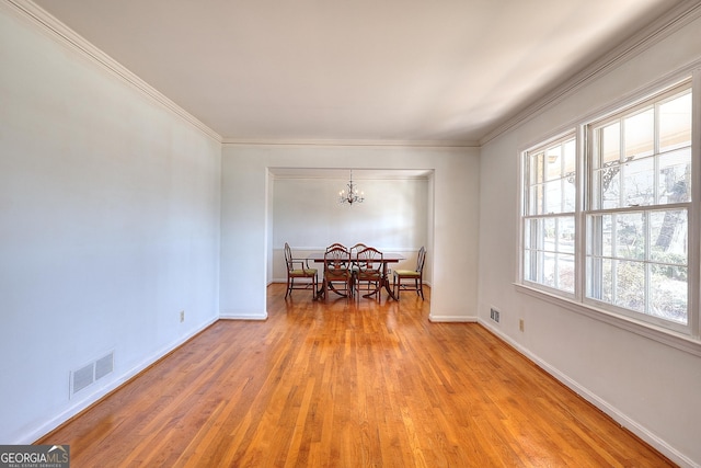 dining room with a notable chandelier, ornamental molding, and light wood-type flooring