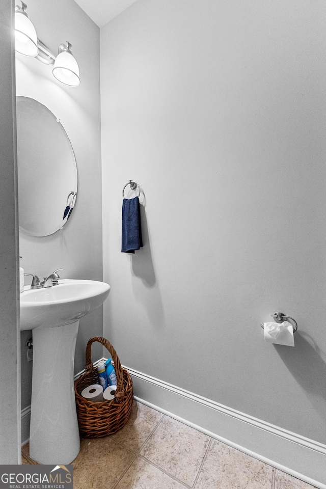 bathroom featuring baseboards, a sink, and tile patterned floors