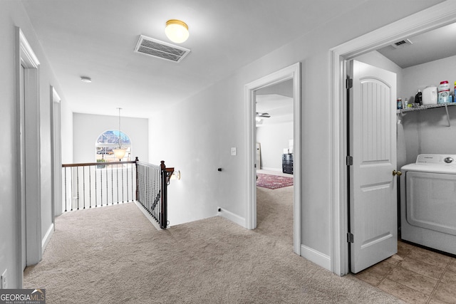 hall featuring an upstairs landing, visible vents, washer / clothes dryer, and light colored carpet