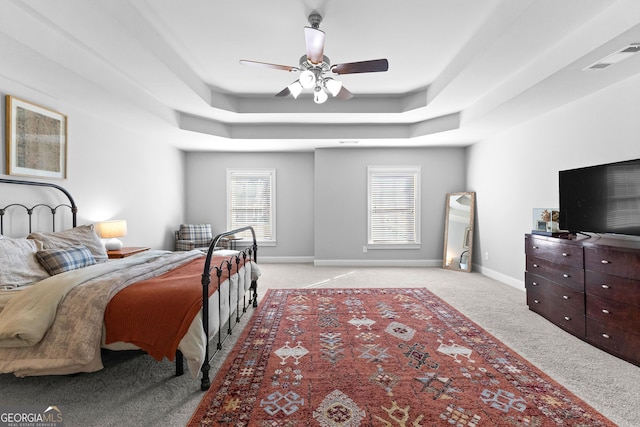 bedroom featuring a raised ceiling, visible vents, a ceiling fan, light carpet, and baseboards