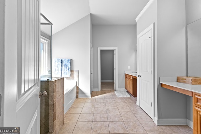 full bath featuring a garden tub, vaulted ceiling, vanity, tile patterned flooring, and baseboards