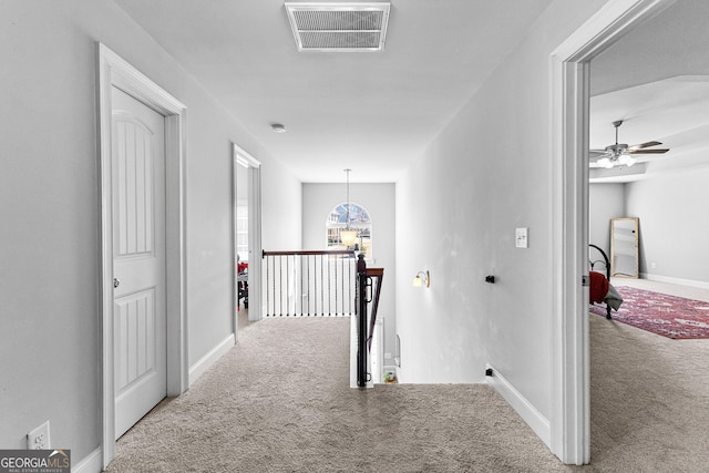 hall with baseboards, visible vents, carpet flooring, and an upstairs landing