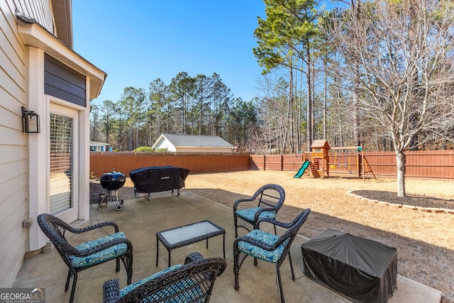 view of patio / terrace featuring a fenced backyard, a grill, and a playground