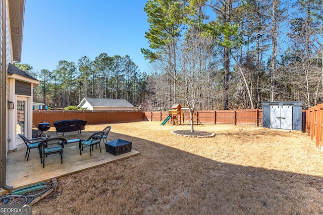 view of yard with a shed, an outbuilding, a playground, and a fenced backyard