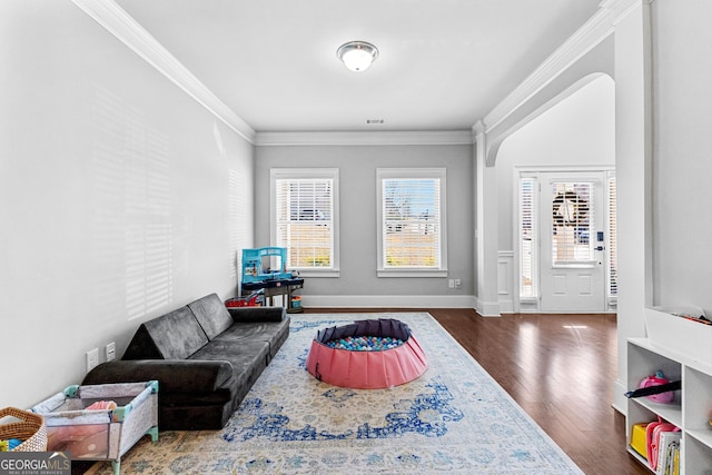 living room featuring dark wood-style floors, baseboards, arched walkways, and crown molding