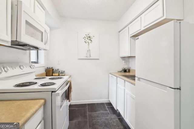 kitchen featuring dark tile patterned flooring, white appliances, and white cabinets