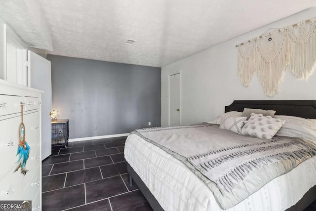 bedroom featuring a textured ceiling and dark tile patterned floors