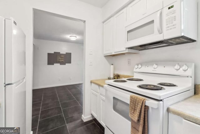 kitchen featuring white appliances, dark tile patterned flooring, and white cabinets