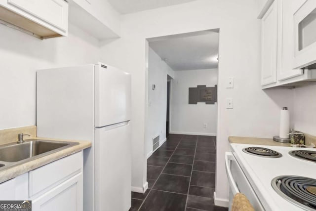 kitchen featuring sink, white appliances, white cabinets, and dark tile patterned flooring