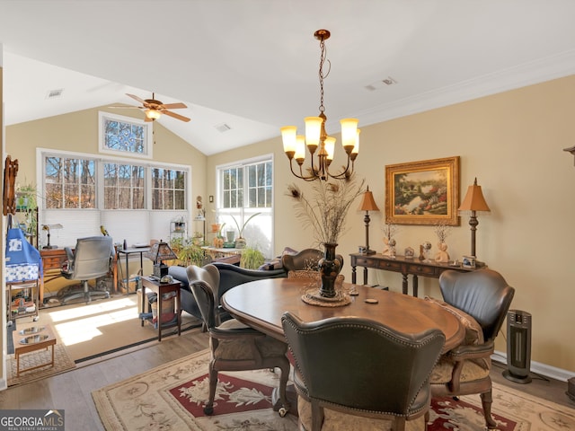 dining area with ceiling fan with notable chandelier, lofted ceiling, and light hardwood / wood-style floors