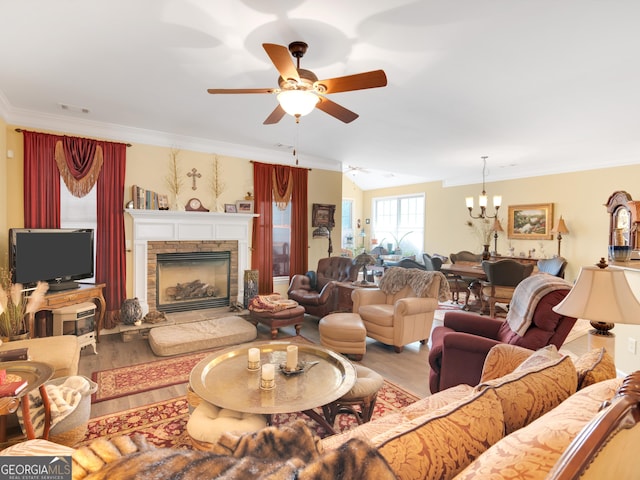 living room featuring hardwood / wood-style floors, ceiling fan with notable chandelier, a fireplace, and ornamental molding