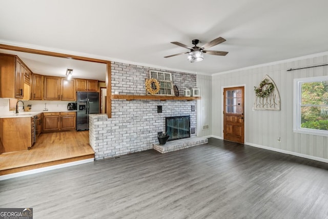 living room with sink, crown molding, hardwood / wood-style flooring, ceiling fan, and a fireplace