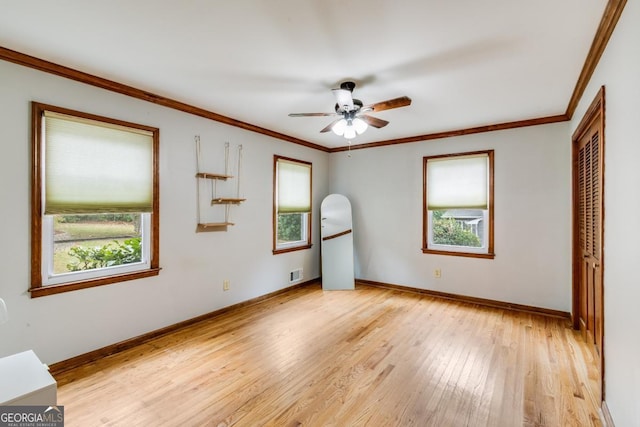 unfurnished bedroom with multiple windows, crown molding, light hardwood / wood-style flooring, and a closet