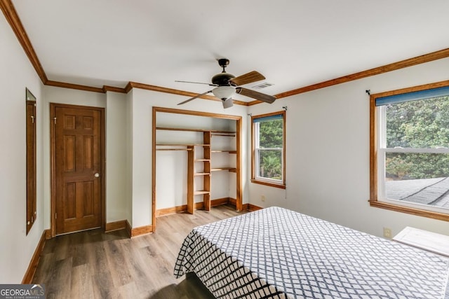 bedroom featuring crown molding, multiple windows, light hardwood / wood-style floors, and a closet