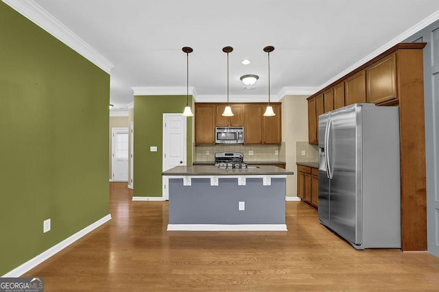 kitchen with crown molding, a breakfast bar area, hanging light fixtures, stainless steel appliances, and an island with sink