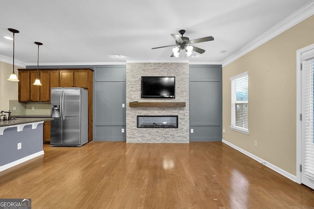 kitchen with pendant lighting, a stone fireplace, stainless steel fridge, and crown molding