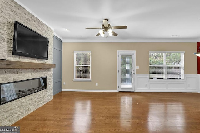 unfurnished living room featuring ceiling fan, ornamental molding, a fireplace, and hardwood / wood-style floors