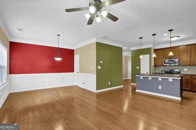 kitchen with wood-type flooring, appliances with stainless steel finishes, a breakfast bar, and decorative light fixtures