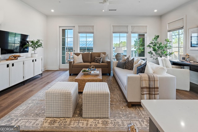 living room featuring dark wood-type flooring and ceiling fan