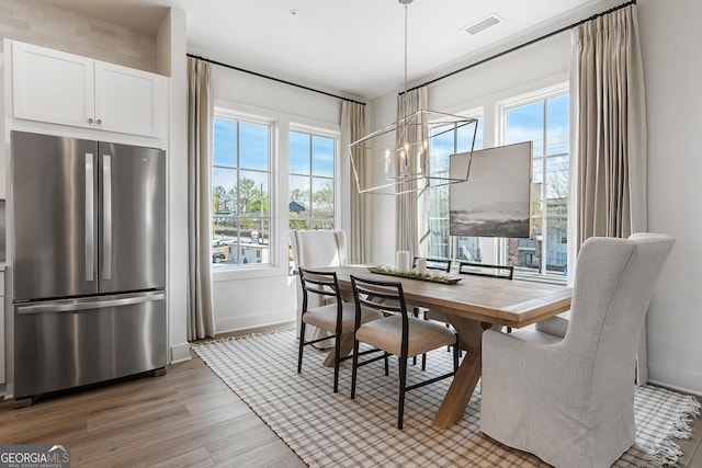 dining area featuring light hardwood / wood-style flooring, plenty of natural light, and a chandelier