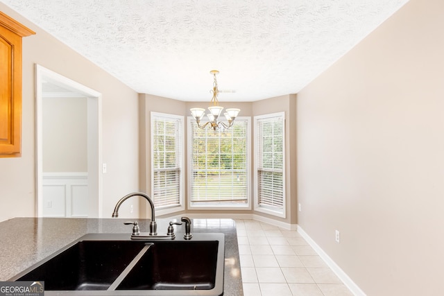 kitchen with light tile patterned flooring, a chandelier, sink, and a textured ceiling