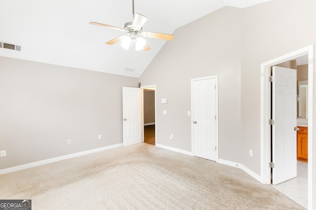 unfurnished bedroom featuring ceiling fan, light colored carpet, connected bathroom, and high vaulted ceiling