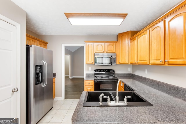 kitchen with sink, stainless steel appliances, and light tile patterned flooring