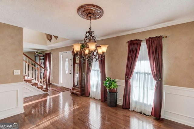 entryway with hardwood / wood-style flooring, ornamental molding, and a chandelier