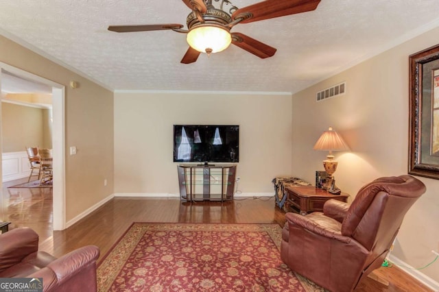 living room with hardwood / wood-style flooring, crown molding, and a textured ceiling