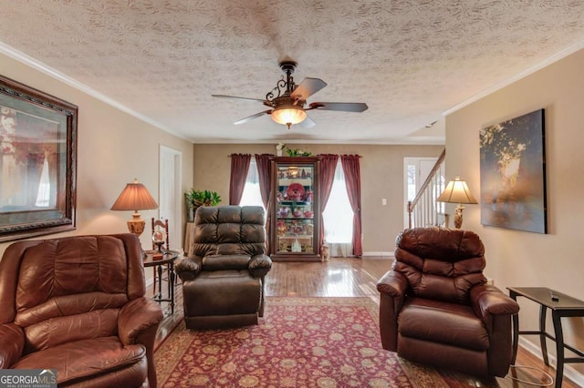 living room featuring crown molding, wood-type flooring, a textured ceiling, and ceiling fan