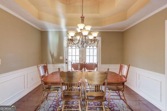 dining room with crown molding, a tray ceiling, dark hardwood / wood-style floors, and a chandelier