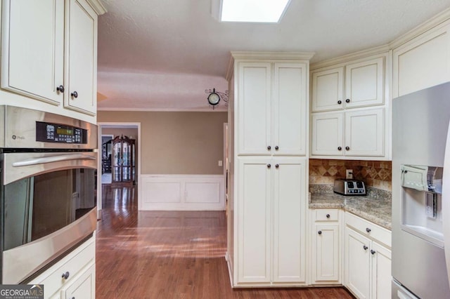 kitchen featuring stainless steel appliances, wood-type flooring, backsplash, and light stone counters