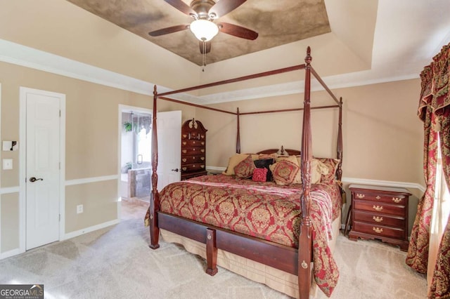 bedroom featuring ensuite bathroom, light colored carpet, ceiling fan, a raised ceiling, and crown molding