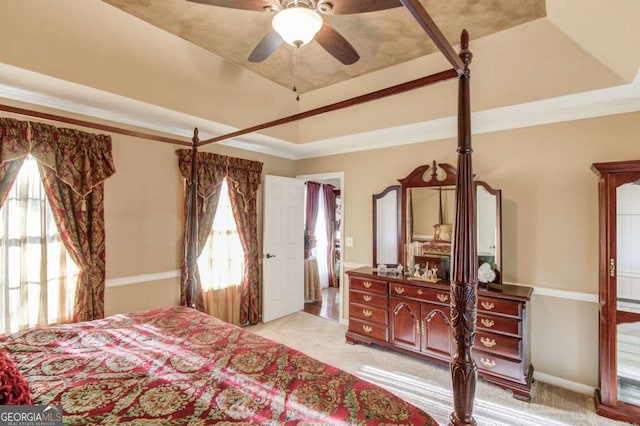 bedroom with ceiling fan, ornamental molding, a tray ceiling, and light carpet